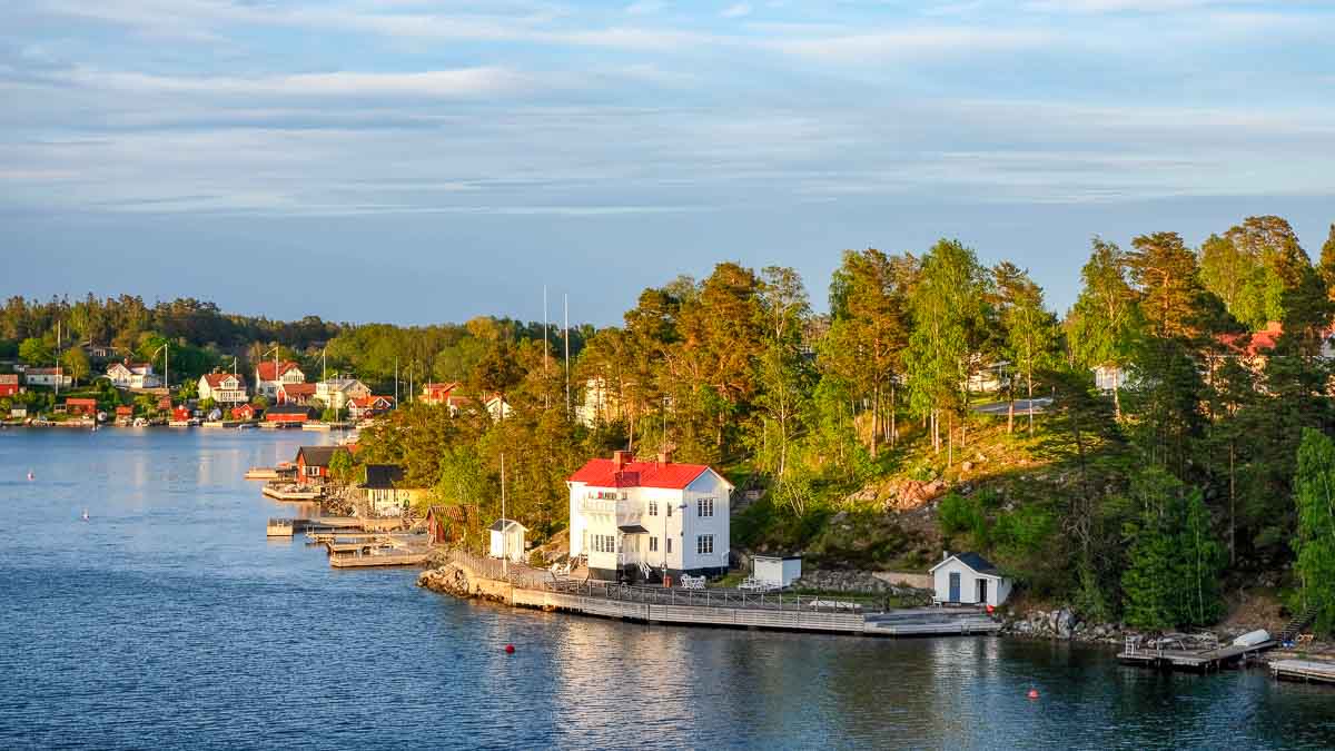 white houses with red roofs on forested shoreline of stockholm's archipelago