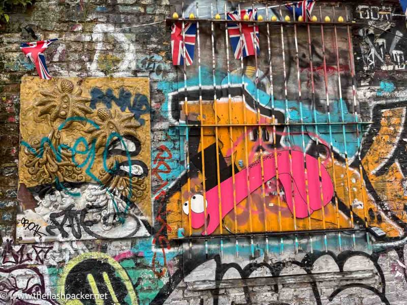 a wall with graffiti and street art and union jack flags