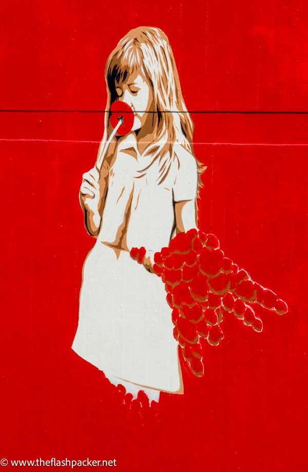 mural of gril in white derss smelling a red flower