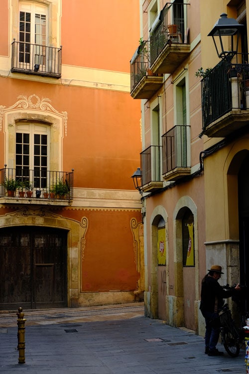 man with bike in narrow medieval street with sand and ochre coloured buildings