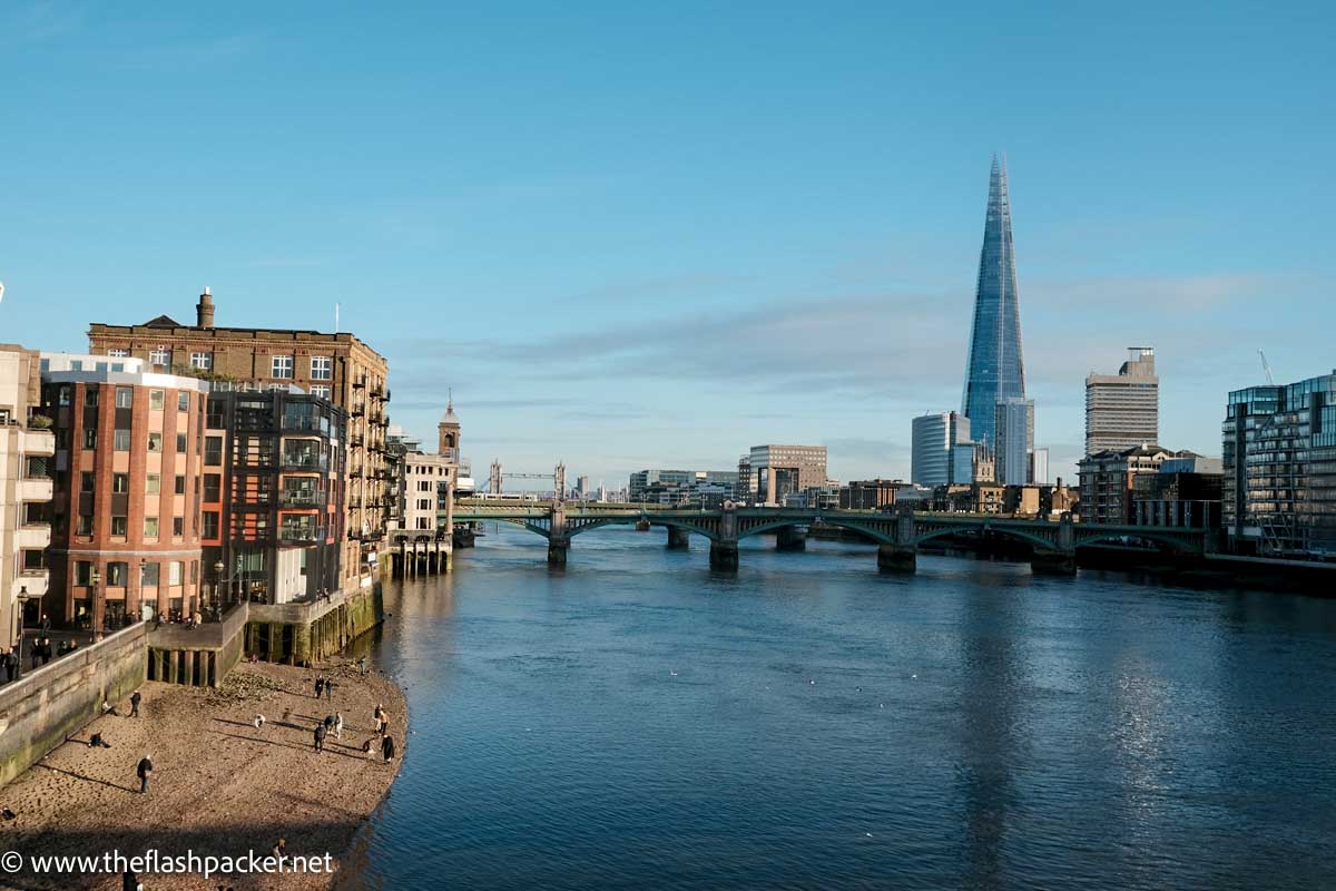 the shoreline of river thames looking towards the shard and london bridge