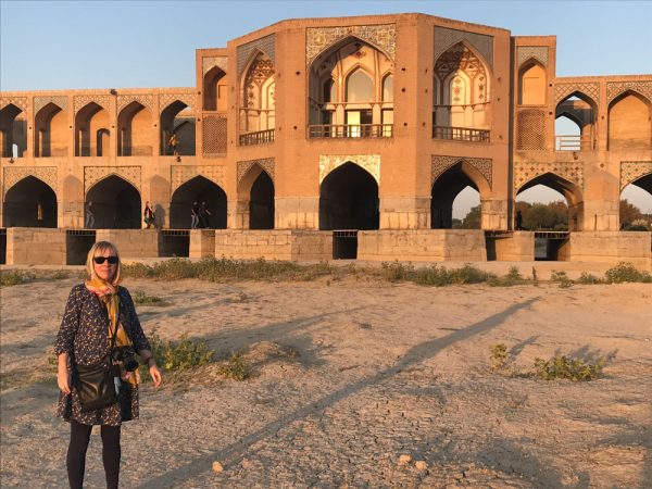 woman posing in front of sandstone bridge in iran