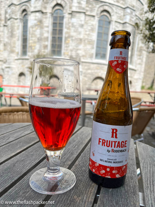 glass of red fruit beer next to a bottle saying fruitage