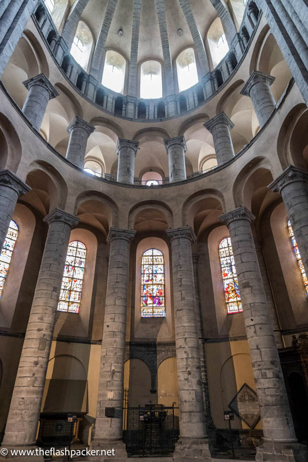 series of slender columns and curved arches in a semi circle in a cathedral transept with stained glass windows