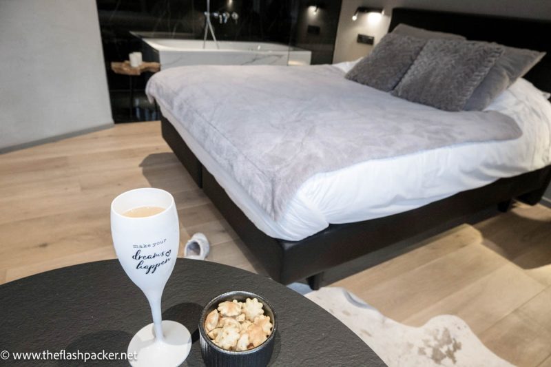 glass of champagne and bowl of crackers in front of large bed at oniro hotel in tournai belgium