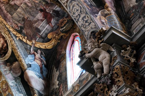 stone sculpture of cherub and richly painted church ceiling