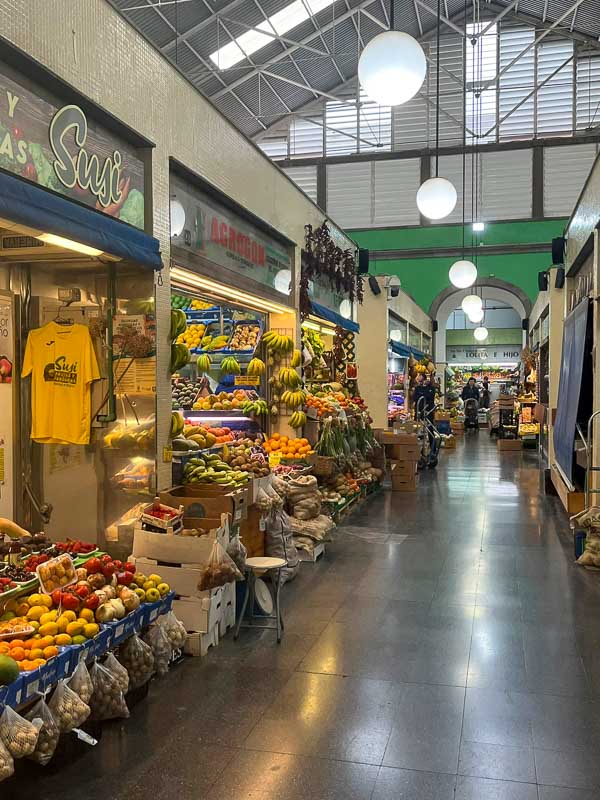 corridor in a covered market with shops selling fruit