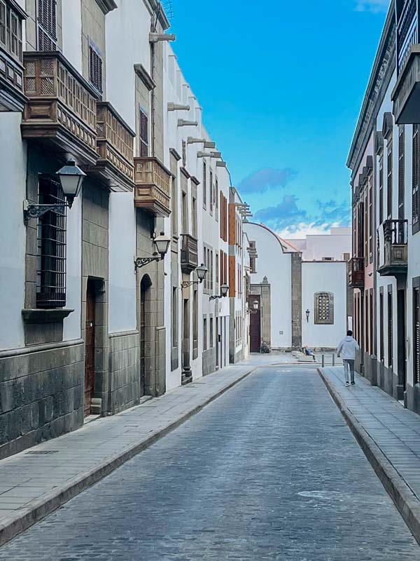 man walking along a street lined with colonial buildings with wooden balconies in las palmas old town