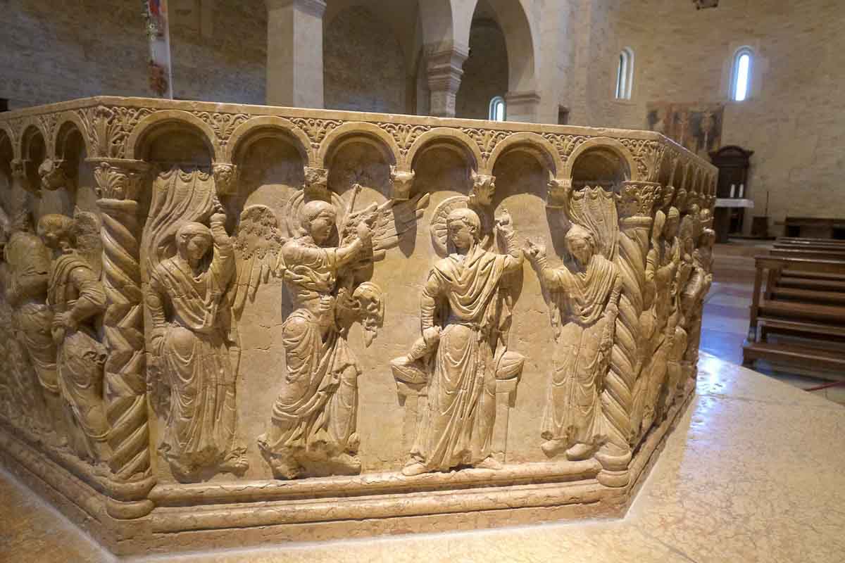 stone baptismal font with carvings of biblical stories