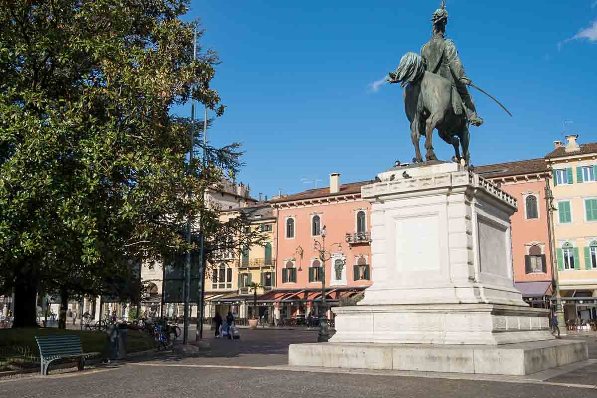 equestrian statue on a white plinth in front of pastel-coloured buildings in piazza bra verona