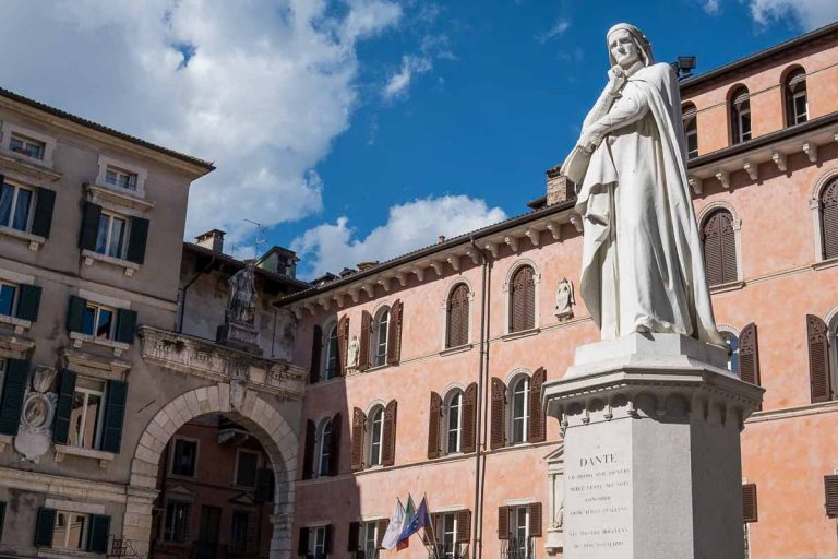 statue of dante in front of a salmon coloured building