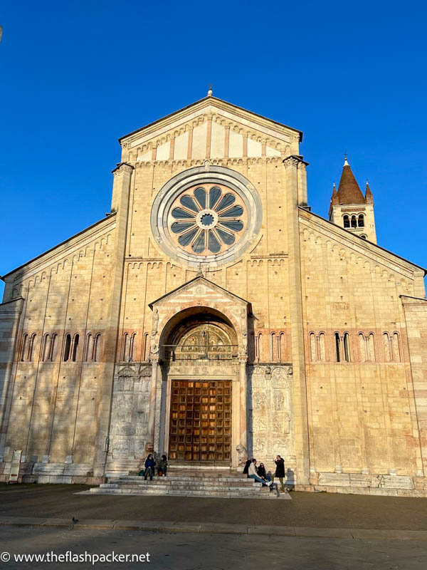 people sitting on the steps outside the facade of san zeno basilica in verona  