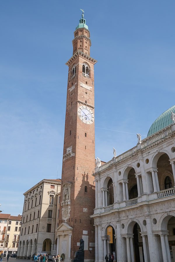 large redbrick bell tower next to a 2-storey white building with loggias