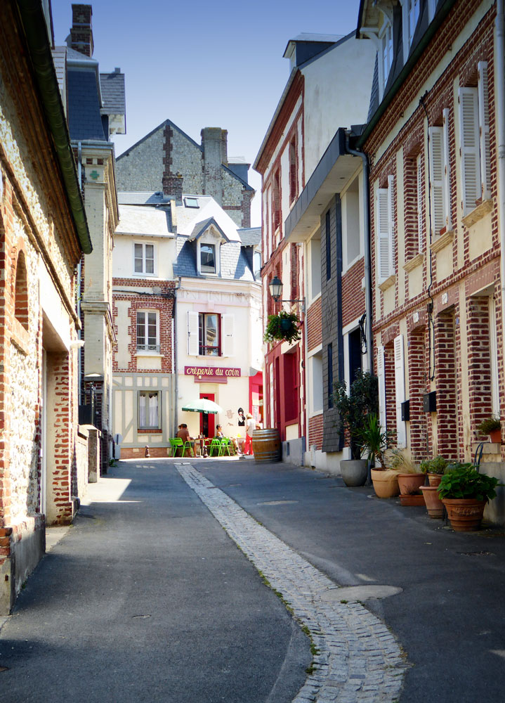 pretty cobblestoned street leading to people dining outside cafe