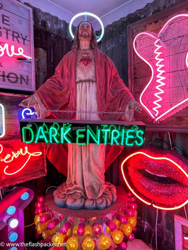 statue of christ surrounded by neon signs