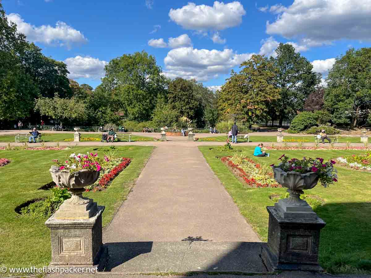 wide path leading through lawn and flower beds in park