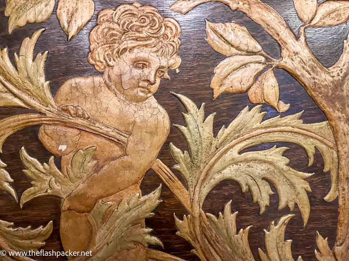 wood carving relief of cherub amongst leaves