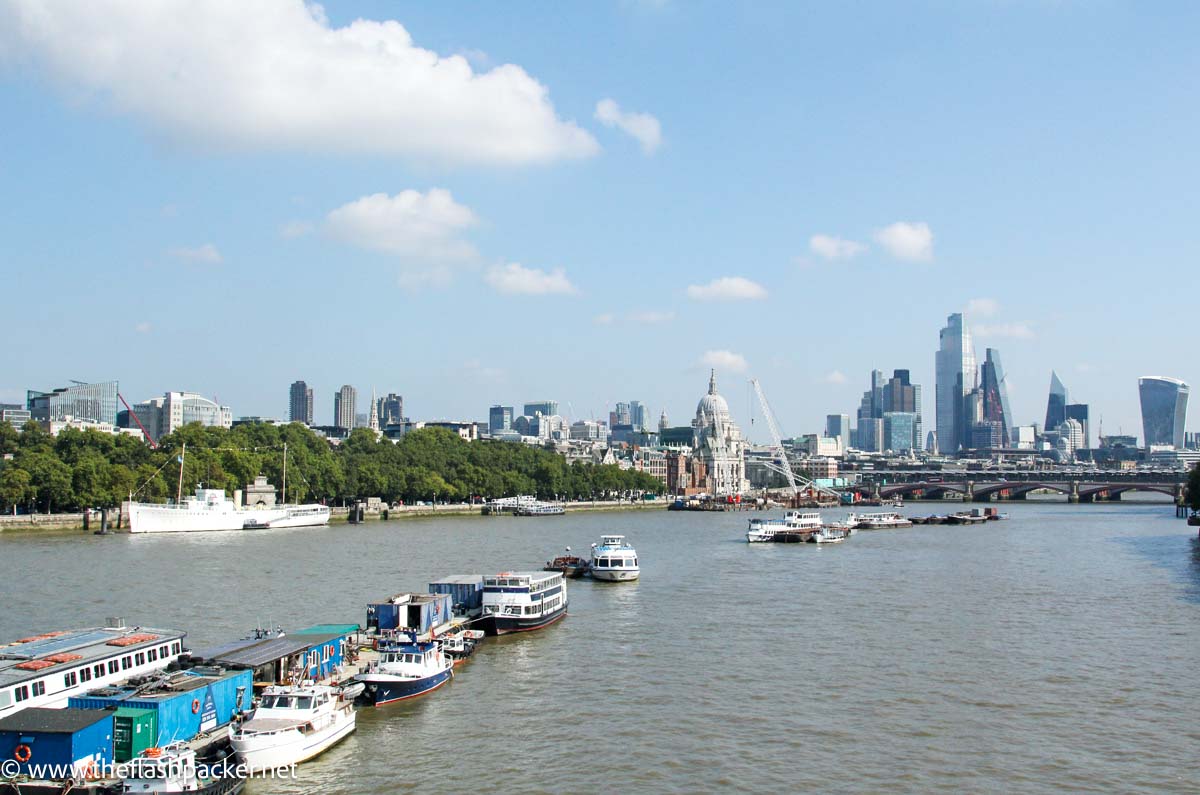 view of river thames with small boats and skyscrapers in distance