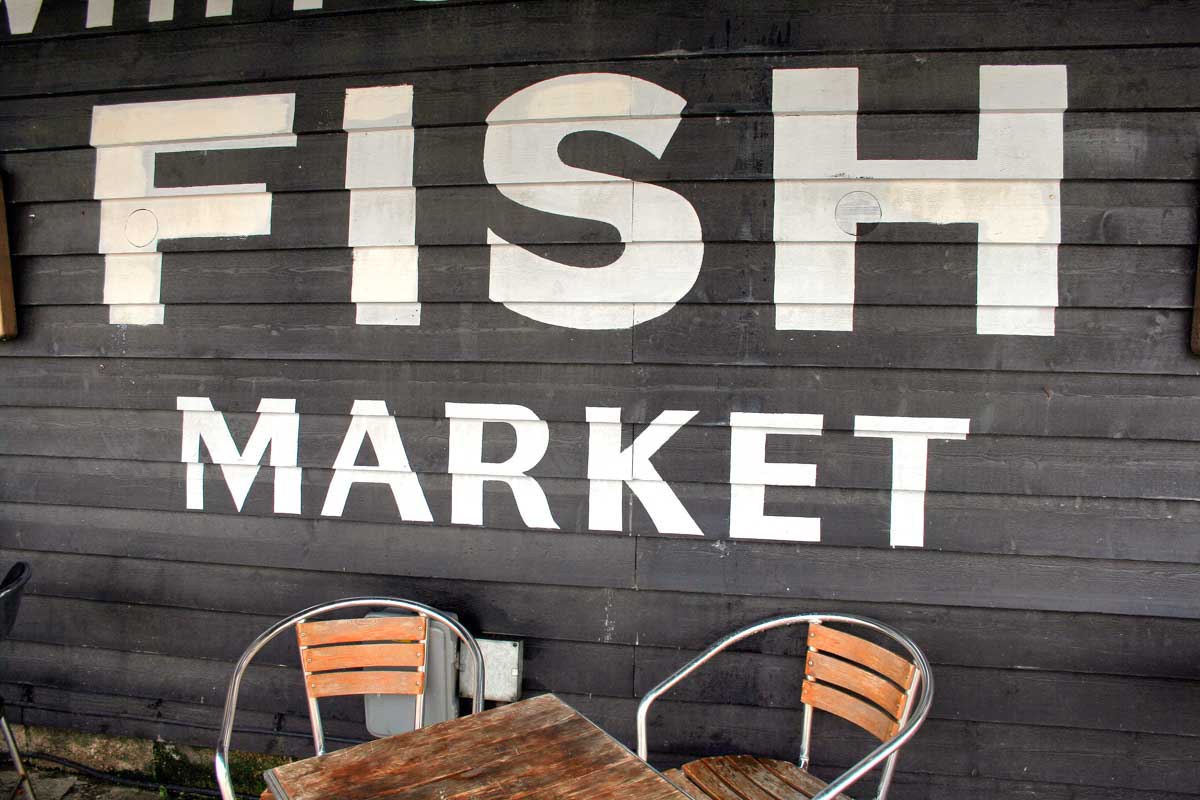 painted sign on wooden building saying fish market