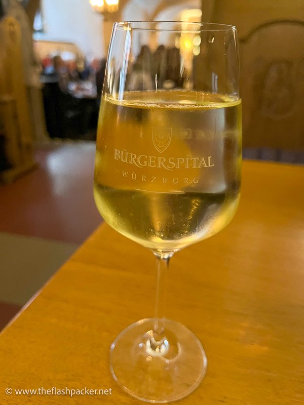 glass of white wine in a glass inscribed with words burgerspital