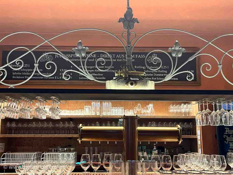 bar in a wine tavern with rows of glasses and a menu board