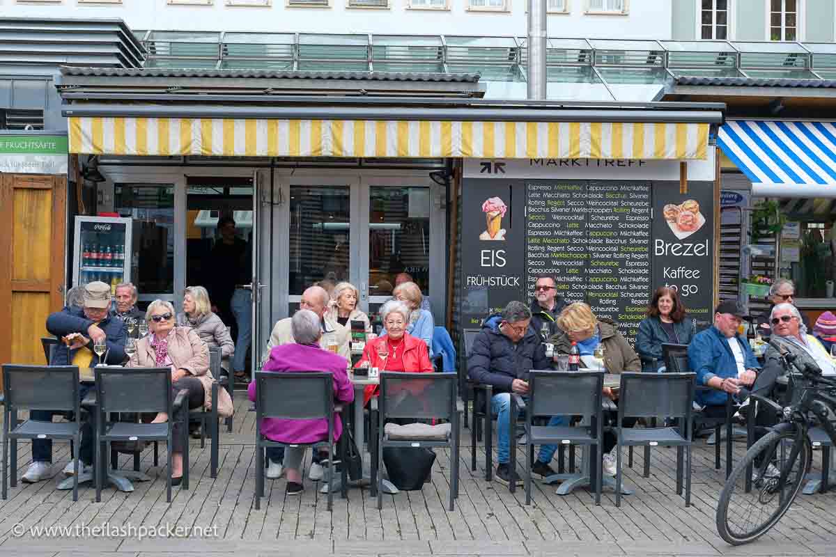 group of people sitting at tables outside a restaurant in germany