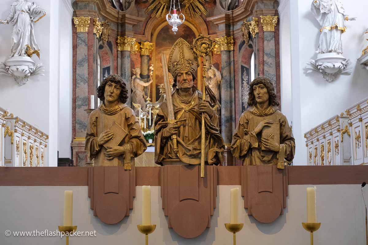 stone figures of 3 saints inside the neuminster in wurzburg