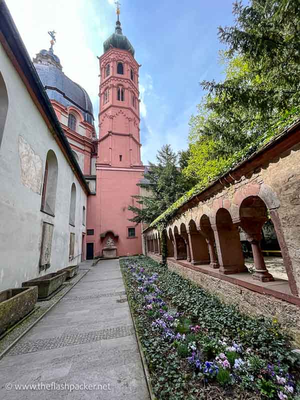 cloister garden leading to a pink-hued church