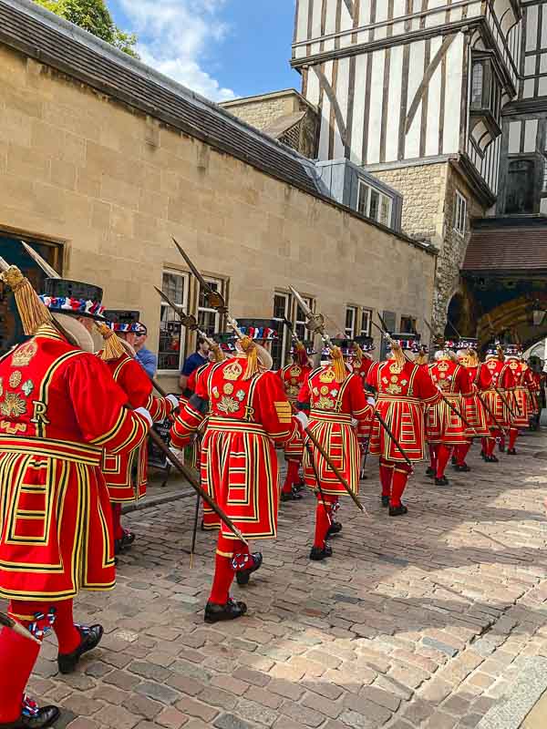 line of marching yeoman warders at tower of london dressed in braided scarlet uniforms