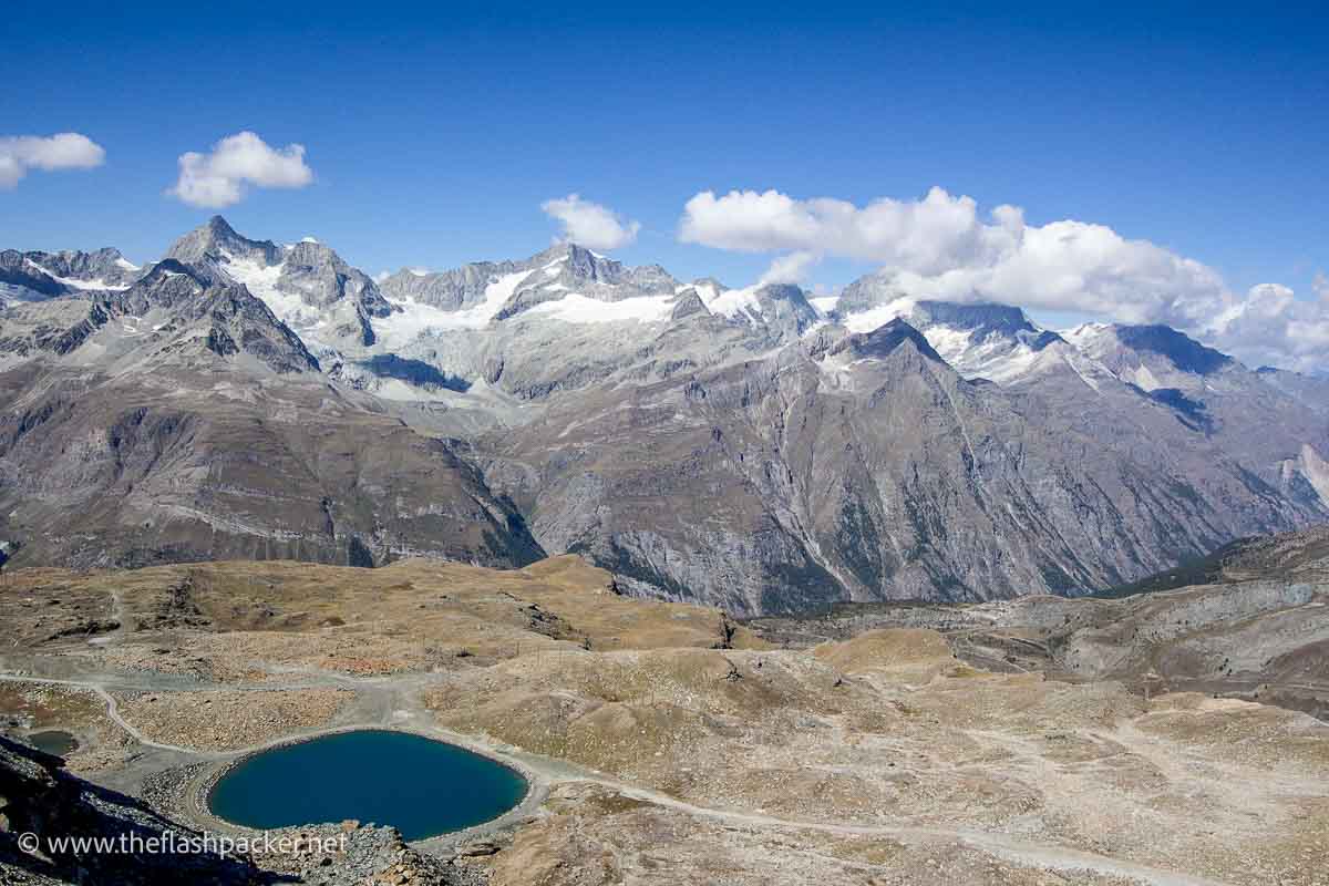 snow capped mountains behind glacier field with pool of water