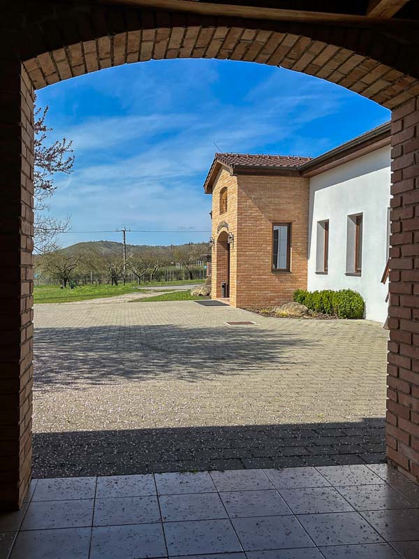 whitewashed and brick building of zidek winery views through an arch